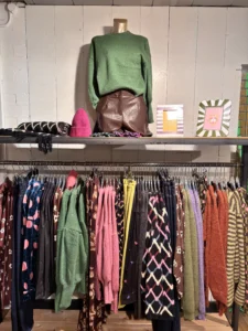 Kledingrek in de winkel met een groene trui en een leren rokje op het schap